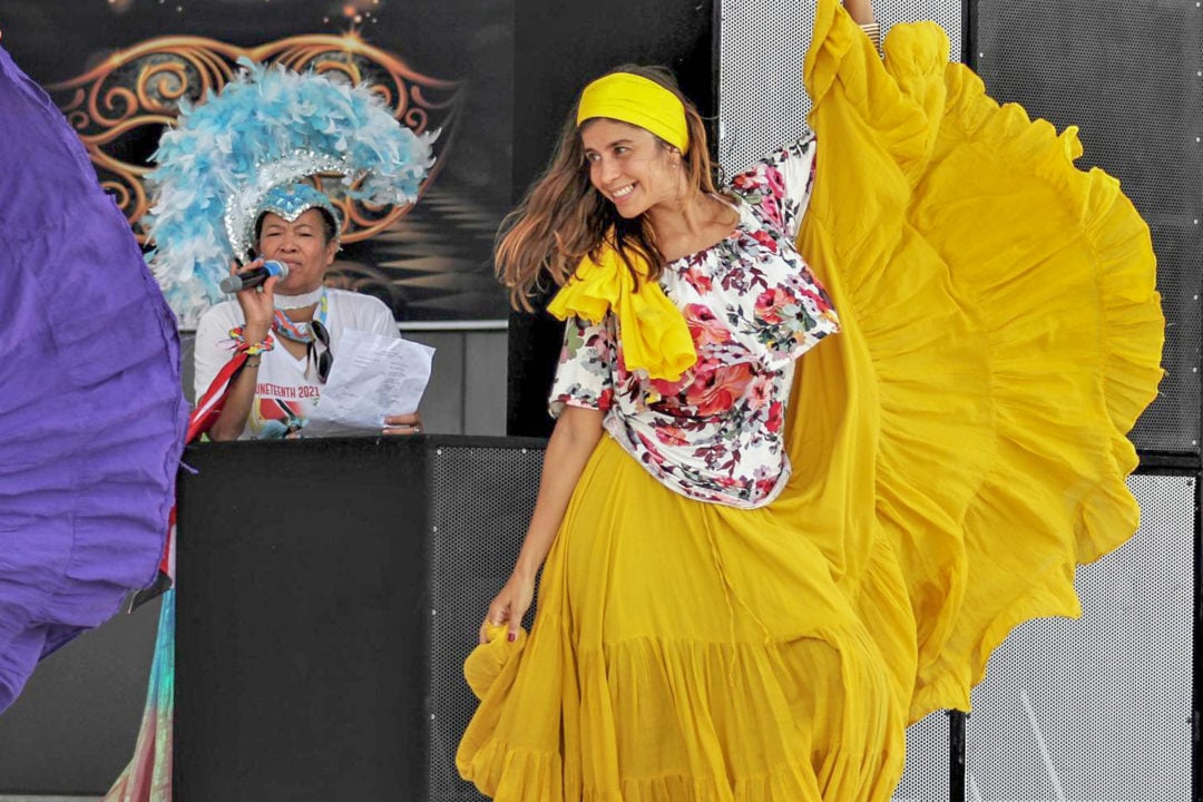 A woman in a bright yellow frilly dress and headband dances