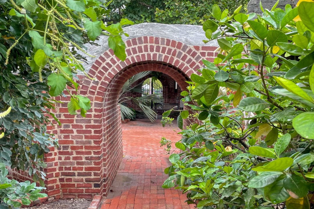 A brick arch surrounded by greenery.
