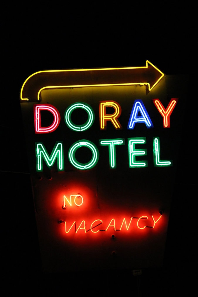 a neon sign at night that reads "doray motel no vacancy"