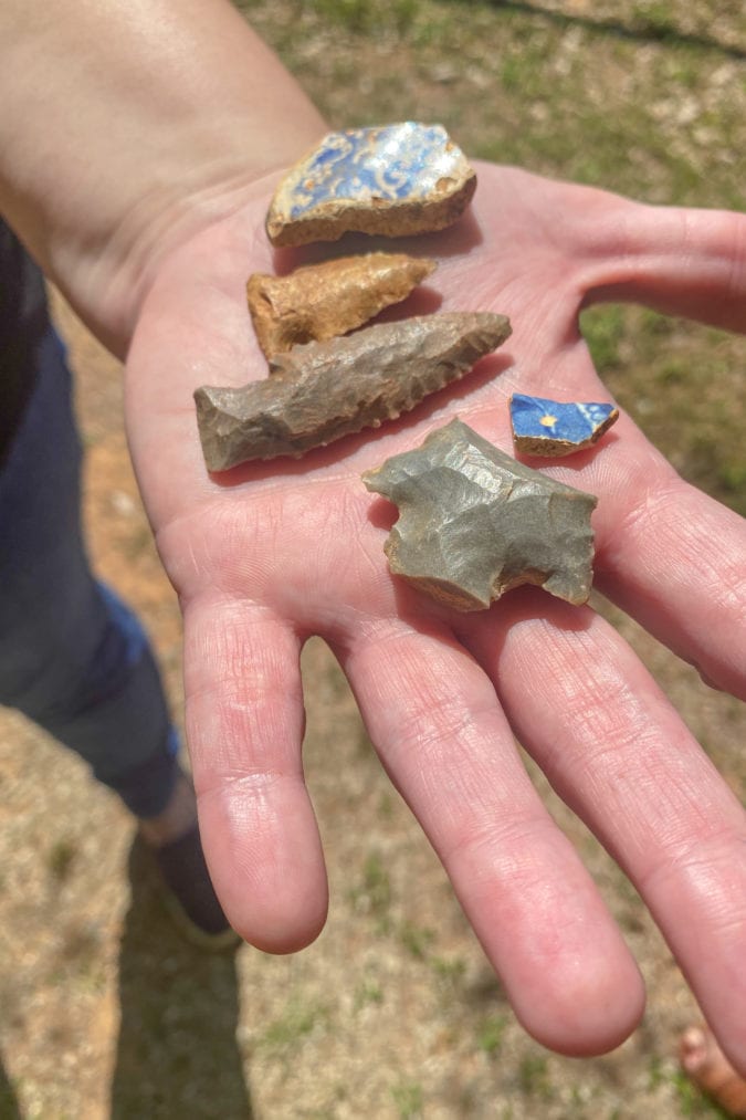 a hand holds stone arrowheads and rocks