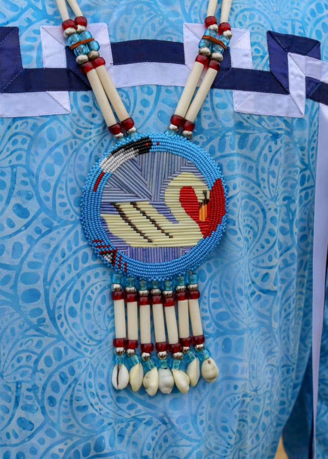 A blue, red and white swan medallion made of dyed quills.
