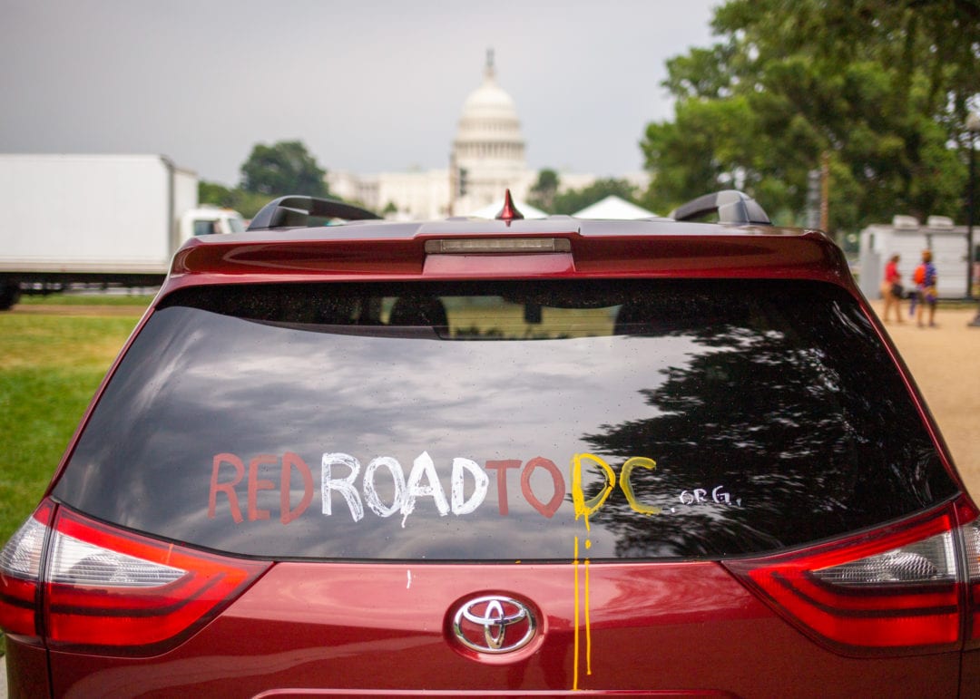 a red car is painted with the message "red road to DC" in front of the capitol