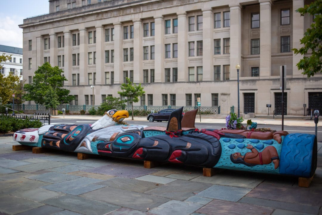 a totem pole lies horizontally outside the department of the interior
