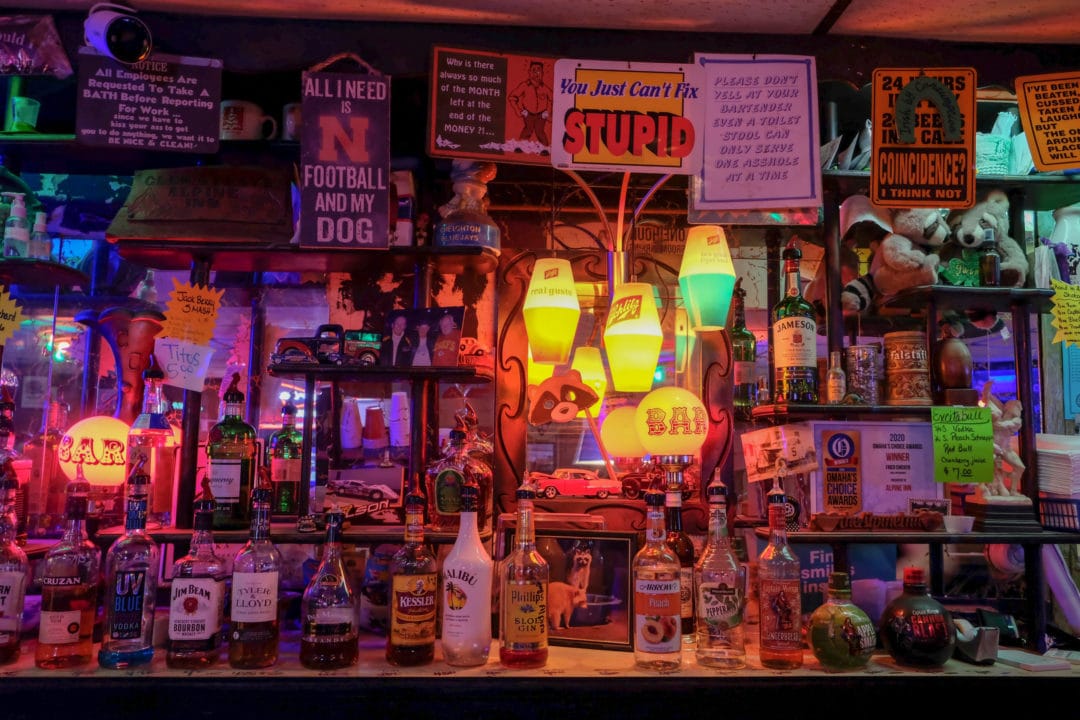 A bar backdrop filled with liquor bottles, raccoon-themed trinkets, and signs
