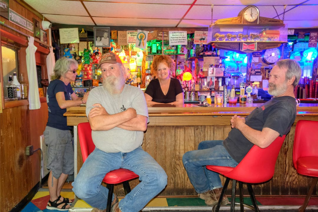 Four people sit and stand around a bar