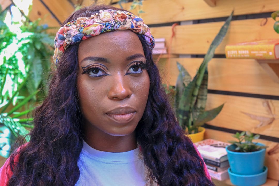 a black woman wears a colorful headband and eyeliner