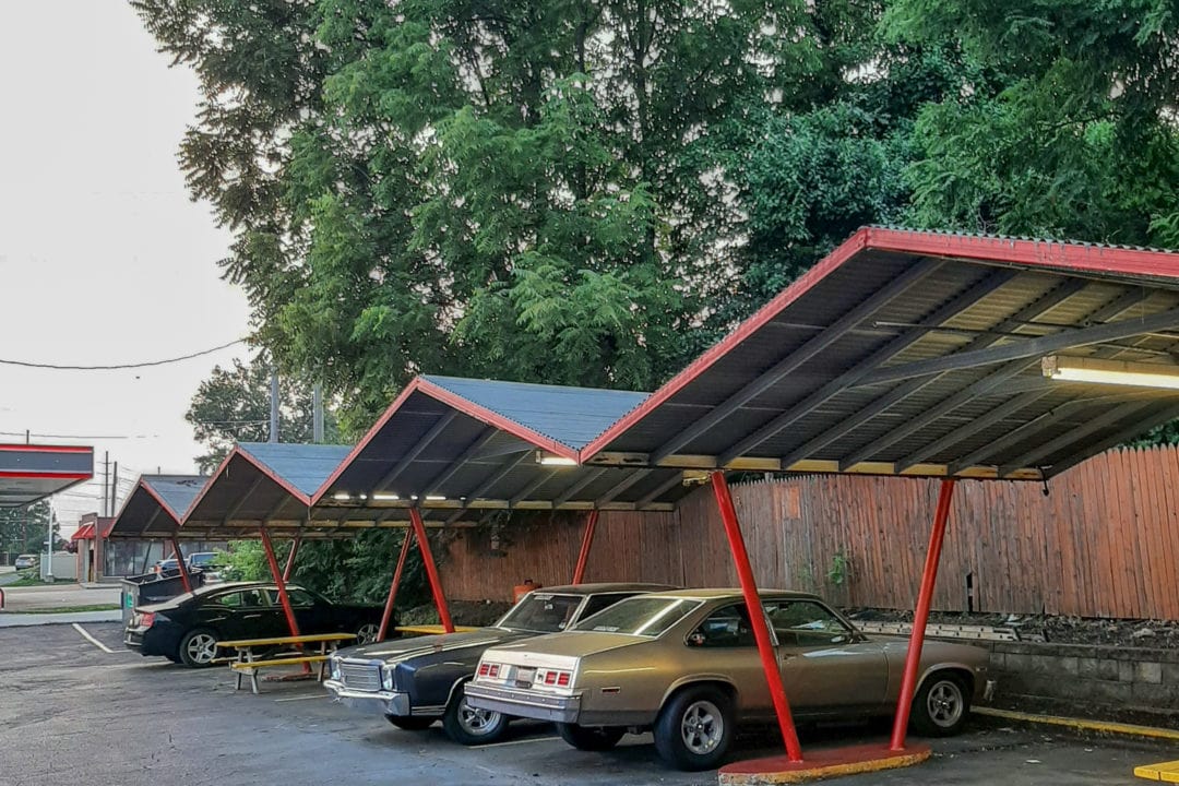 classic cars parked under a car port with a zig zag roof