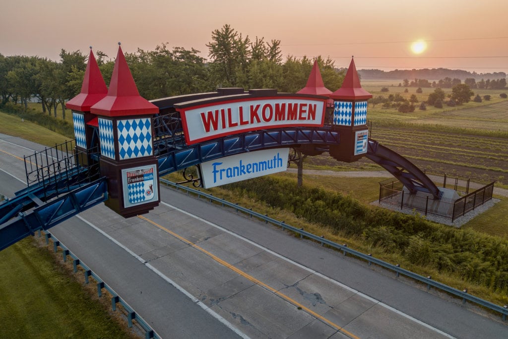 a red and blue sign stretching across a road that reads "willkommen frankenmuth"