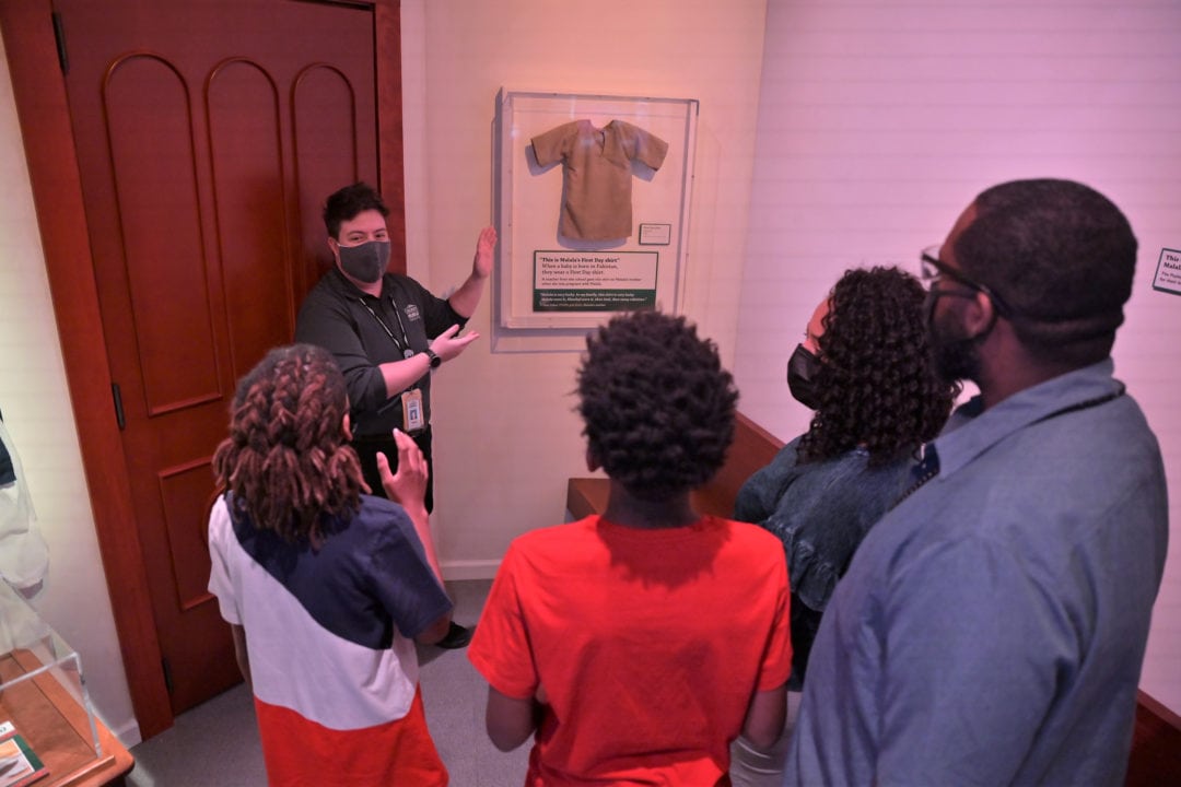 a guide explains the significance of a shirt on display to a group of people