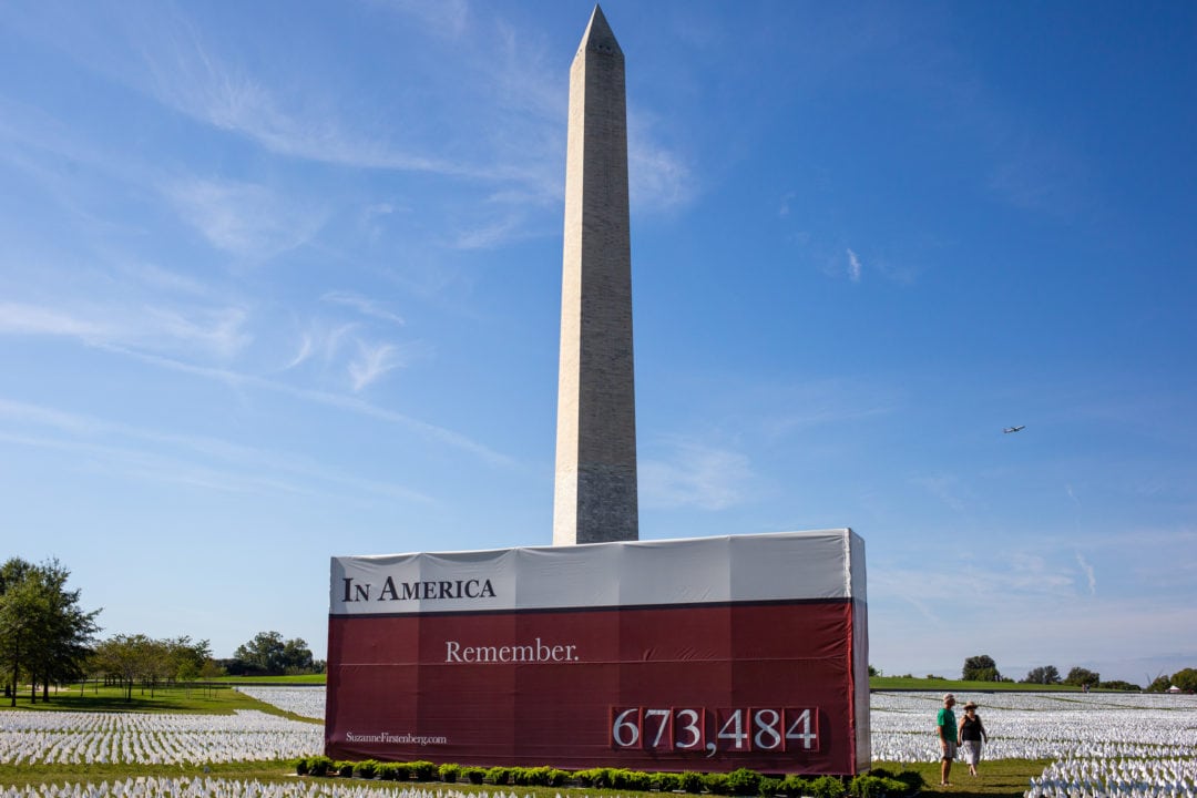 the washington monument and a sign for the in america remember installation in the afternoon