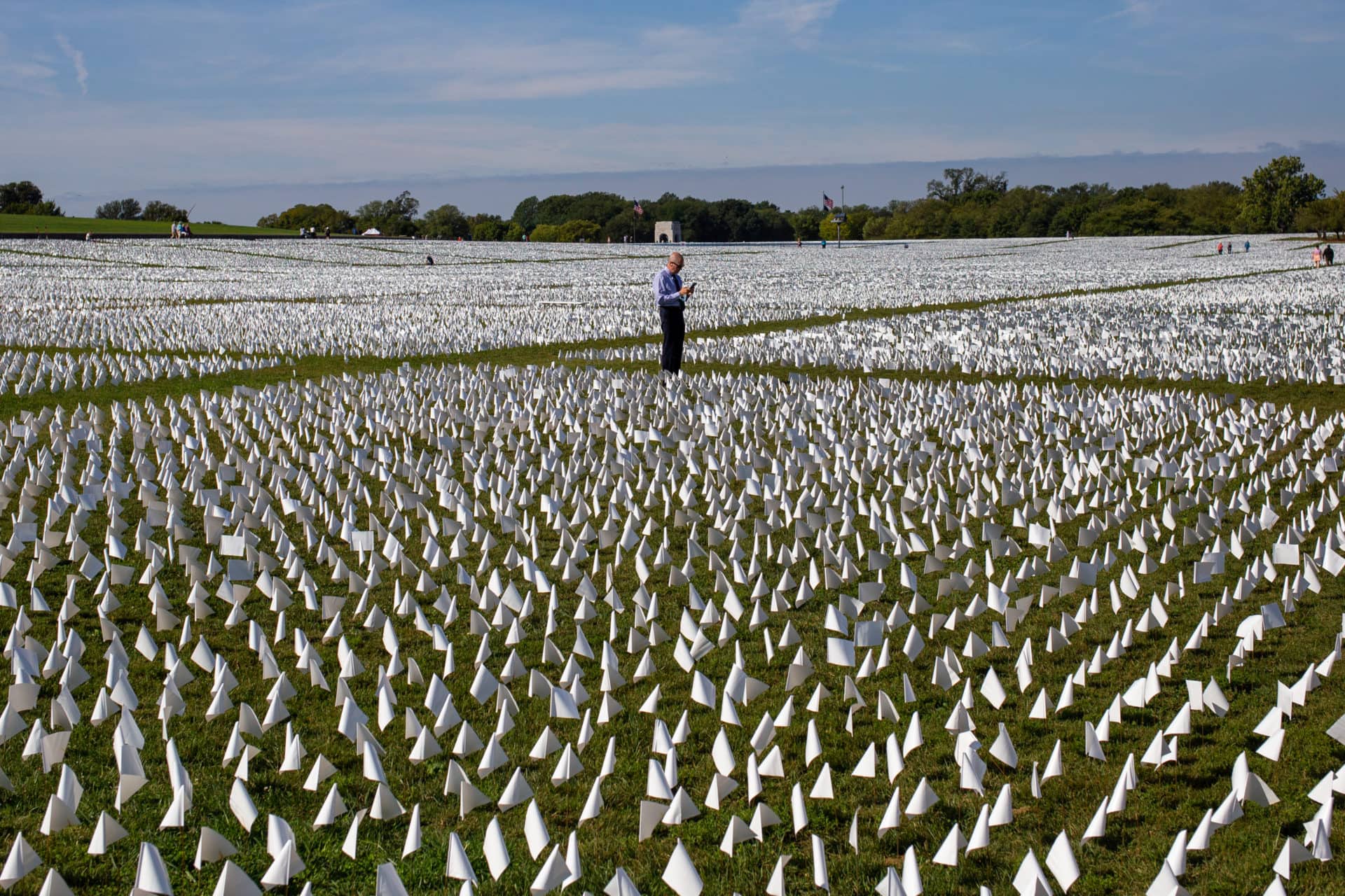 a man stands in the middle of a sea of white flags
