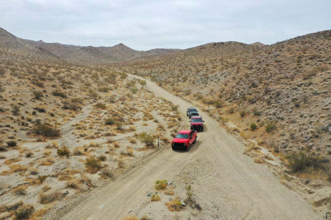 Three pickup trucks on a desert trail, seen from above
