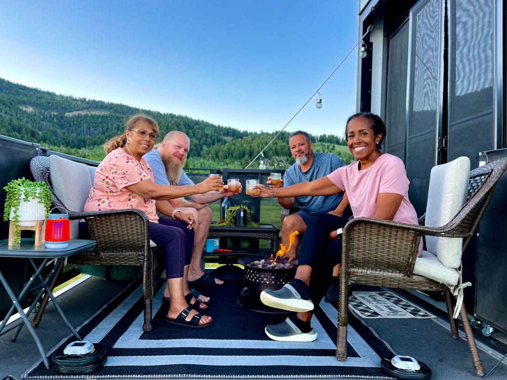 Four people seated on an RV patio and holding up their drinks