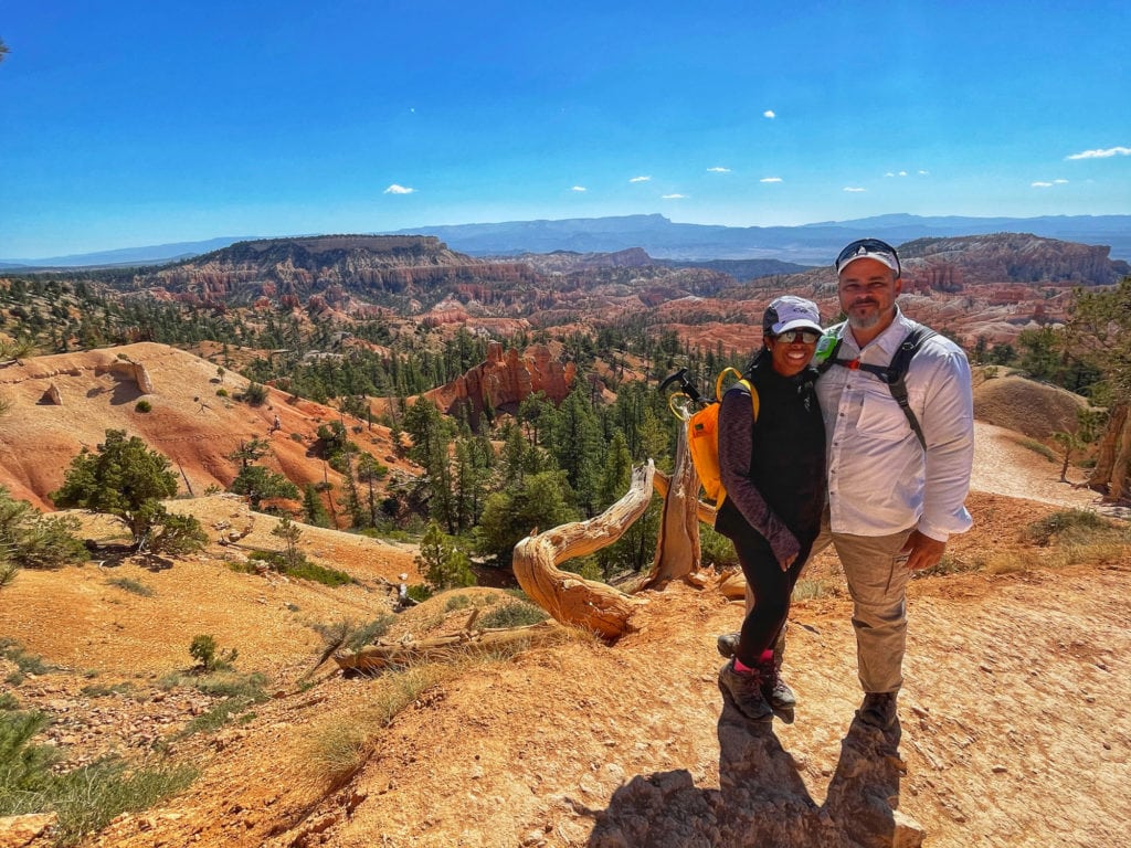 A couple in hiking clothes with a scenic canyon view behind them