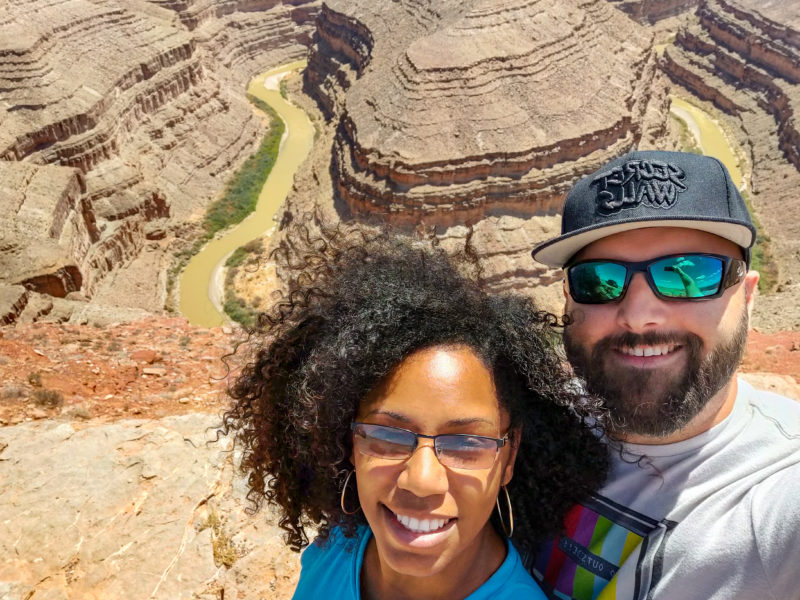 two people pose for a photo in front of a large canyon