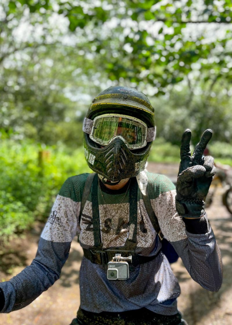 A person covered in mud wearing a helmet 