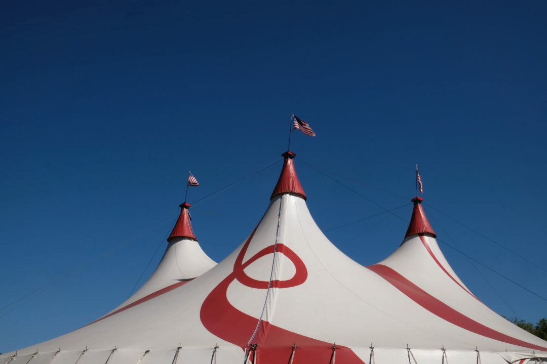 a red-and-white-striped circus tent against a blue sky