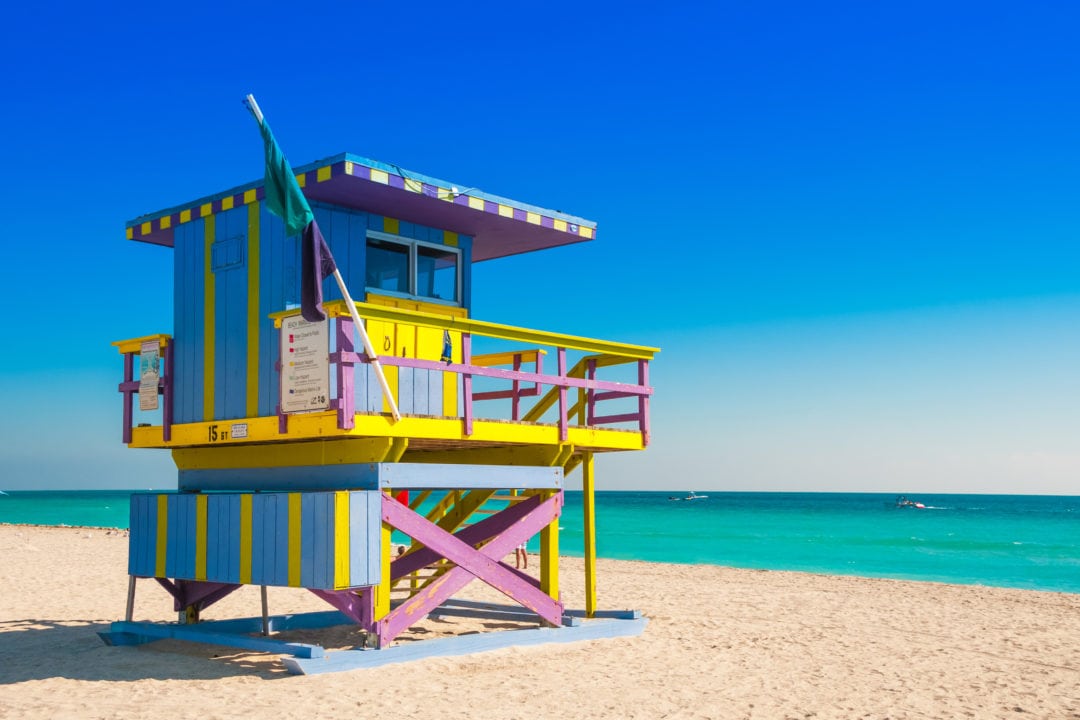 a colorful wooden lifeguard tower sits on a beach