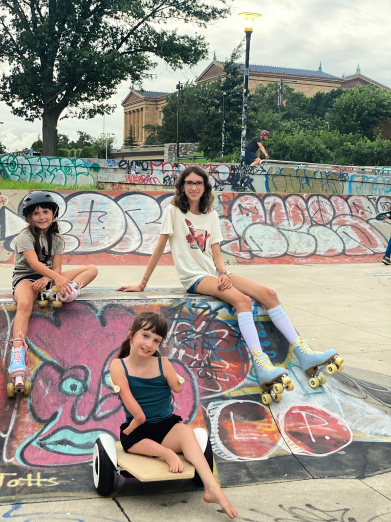 three girls sit at a skate park