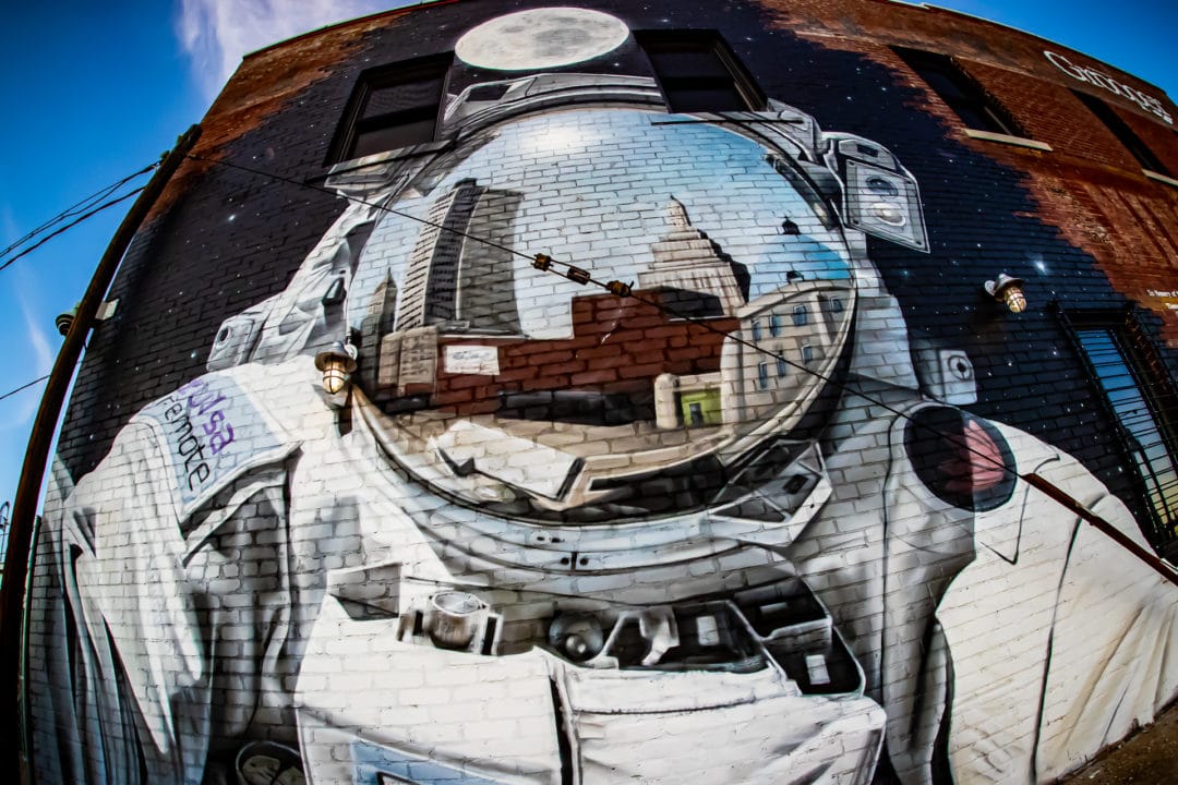 Mural of astronaut with city skyline reflection in mask