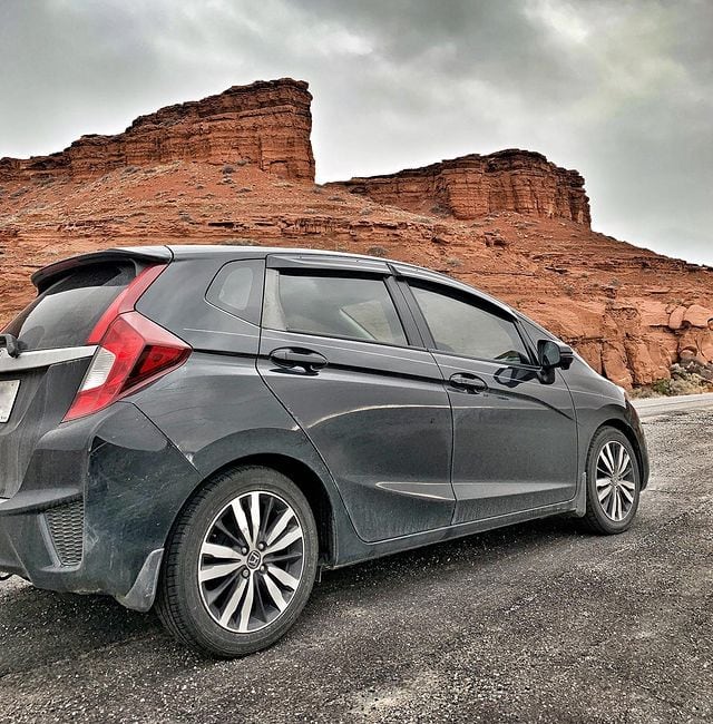 A Honda Fit car with red rocks in the background
