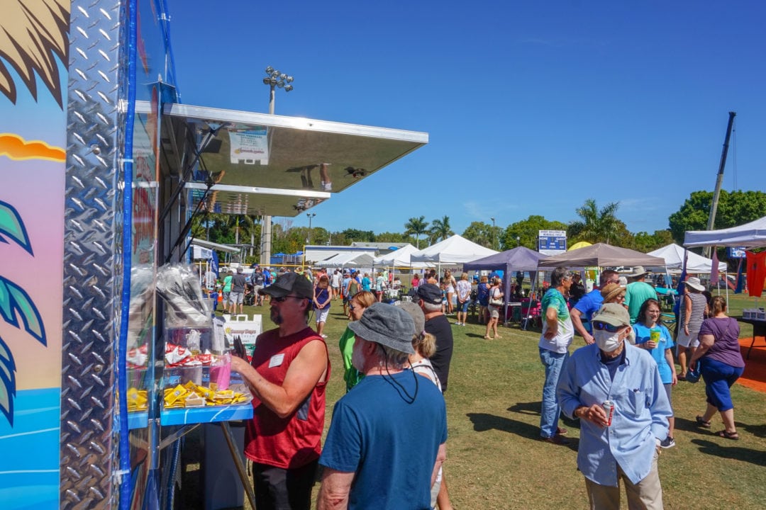 a crowd at an outdoor festival with food vendors