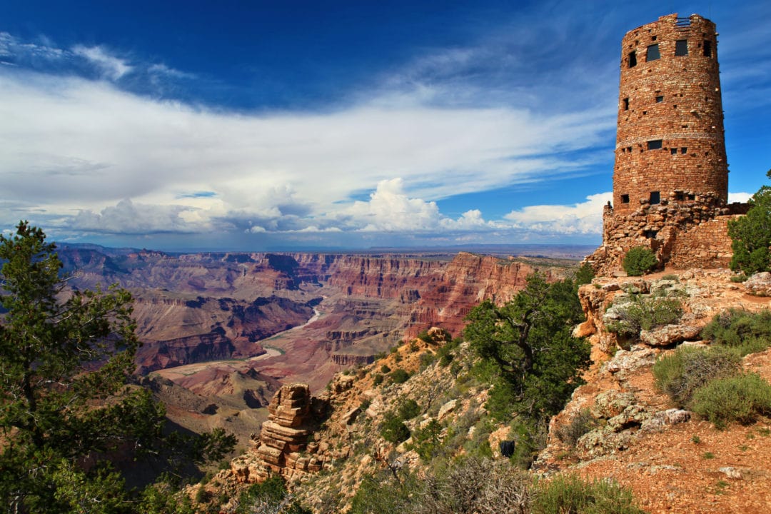 a stone tower is perched on a cliff overlooking the grand canyon