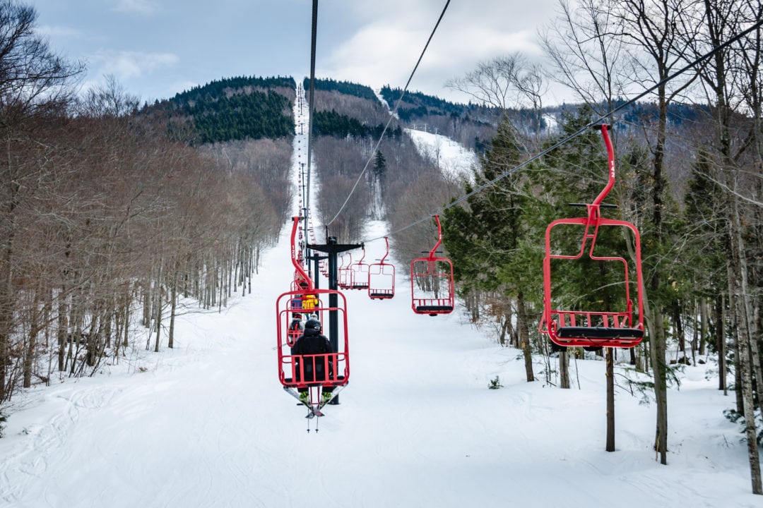 red chairs on a ski lift over a snowy mountain
