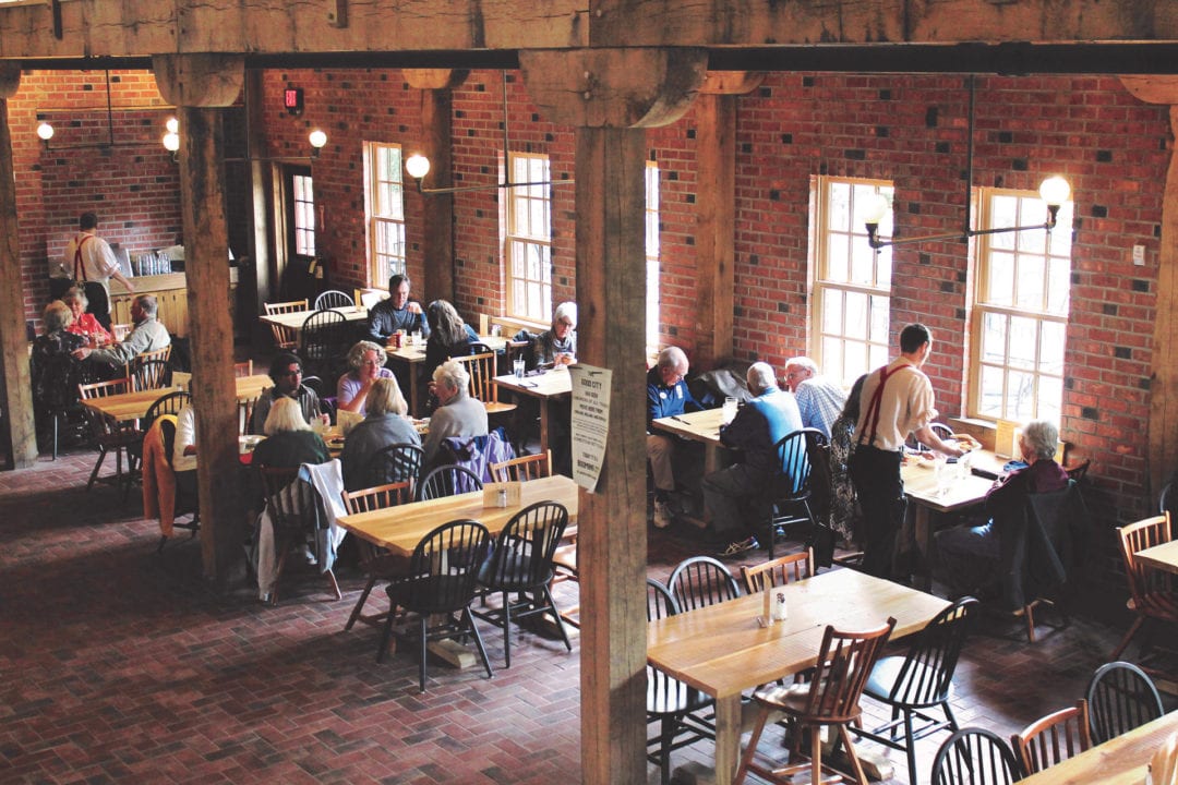 Brick walled large open room with dining table and chairs about half filled with patrons