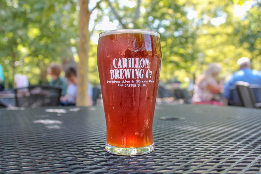 Full pint of red-orange colored beer sitting on outdoor table