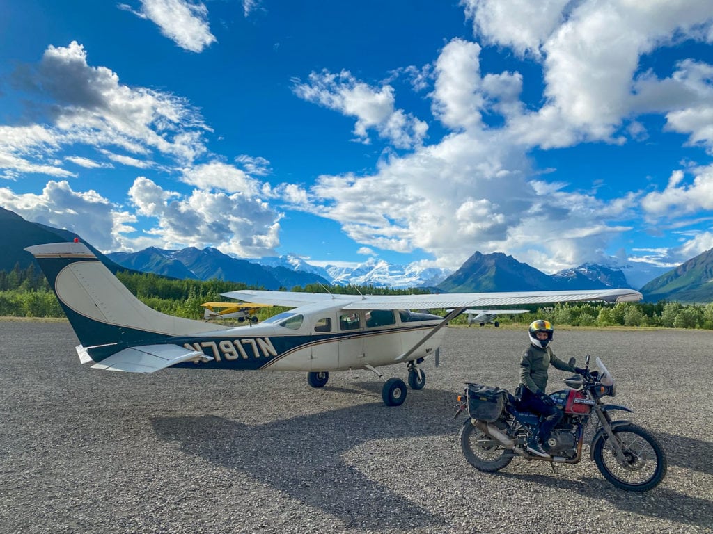 A person sitting on a motorcycle next to a small airplane