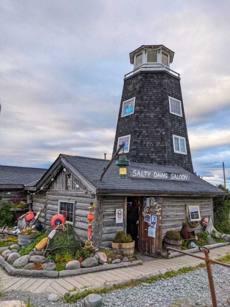 The exterior of a bar called Salty Dog Saloon, with a lighthouse tower on top of it