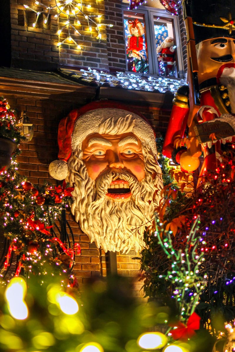 A menacing-looking Santa hed on a wall, surrounded by lights