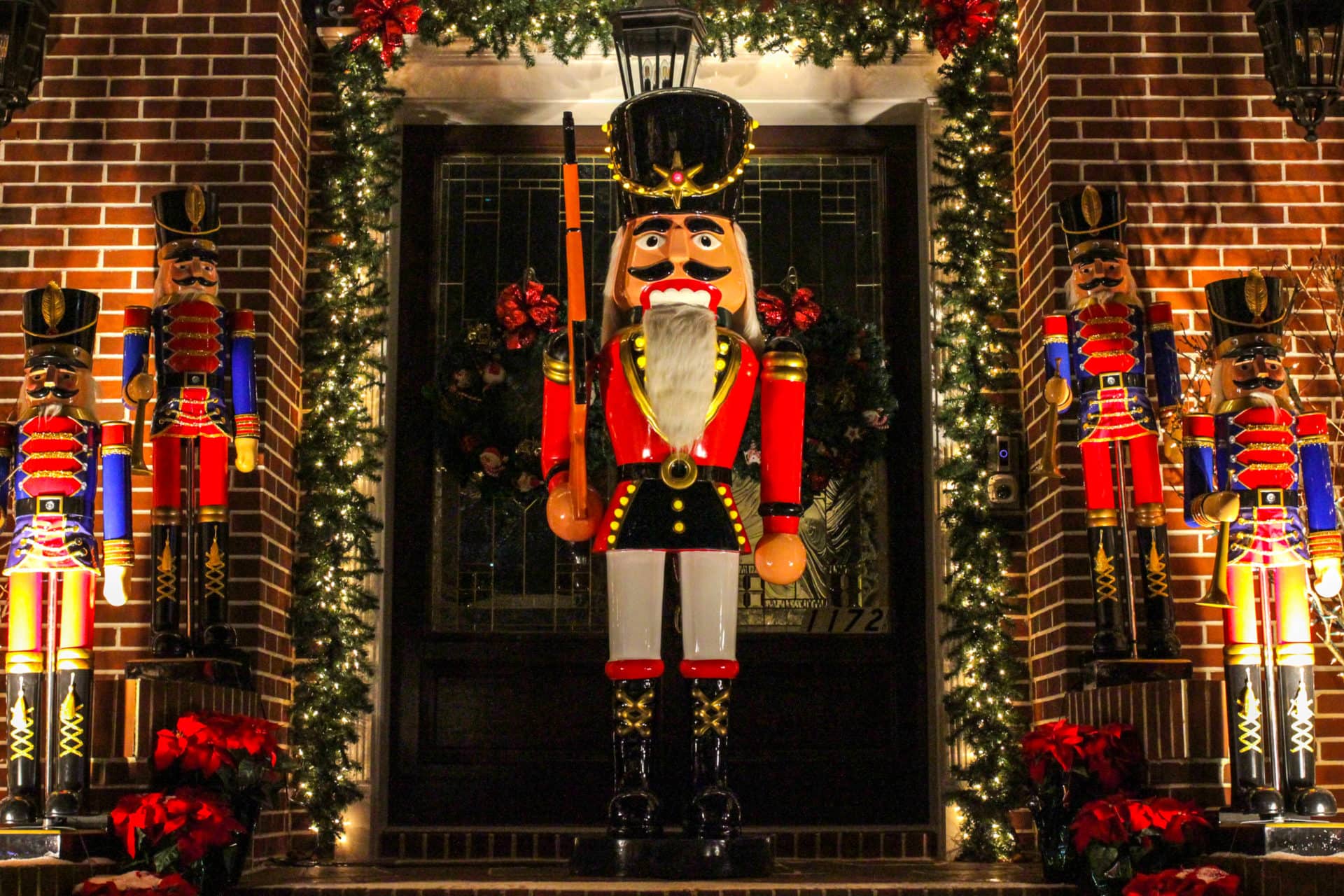 A large nutcracker stands guard in front of a door, surrounded by smaller nutcrackers 