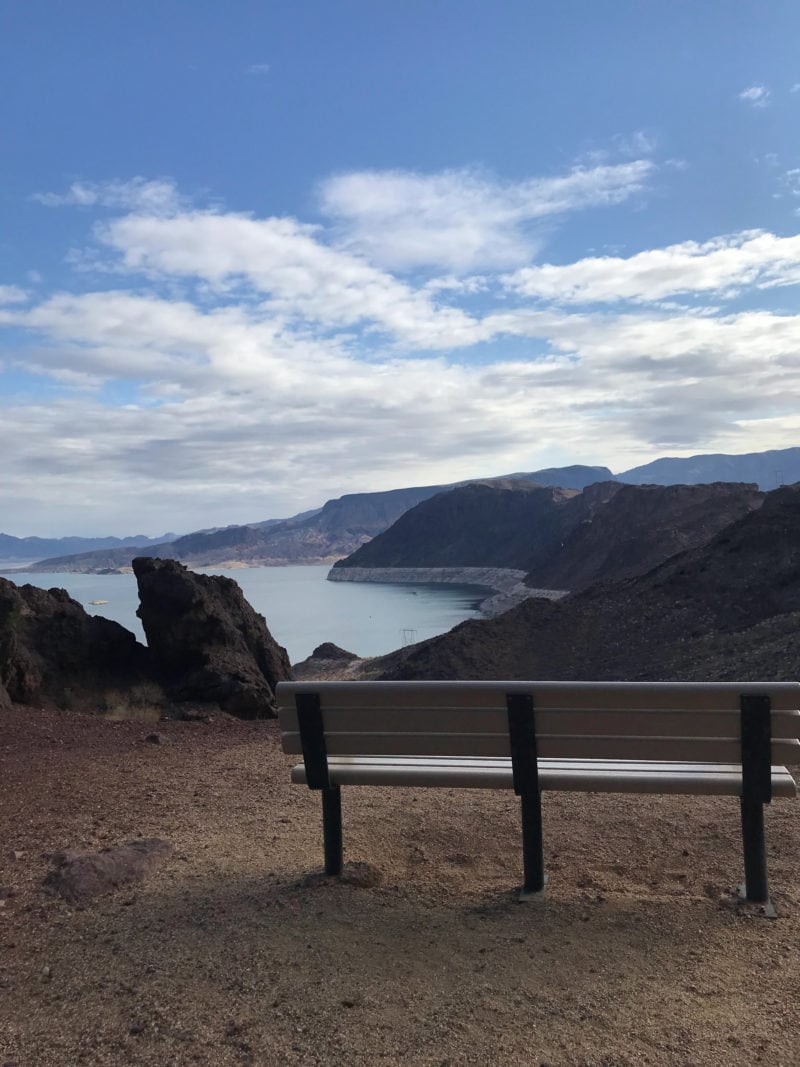 a bench sits on an over look with scenic views of lake mead