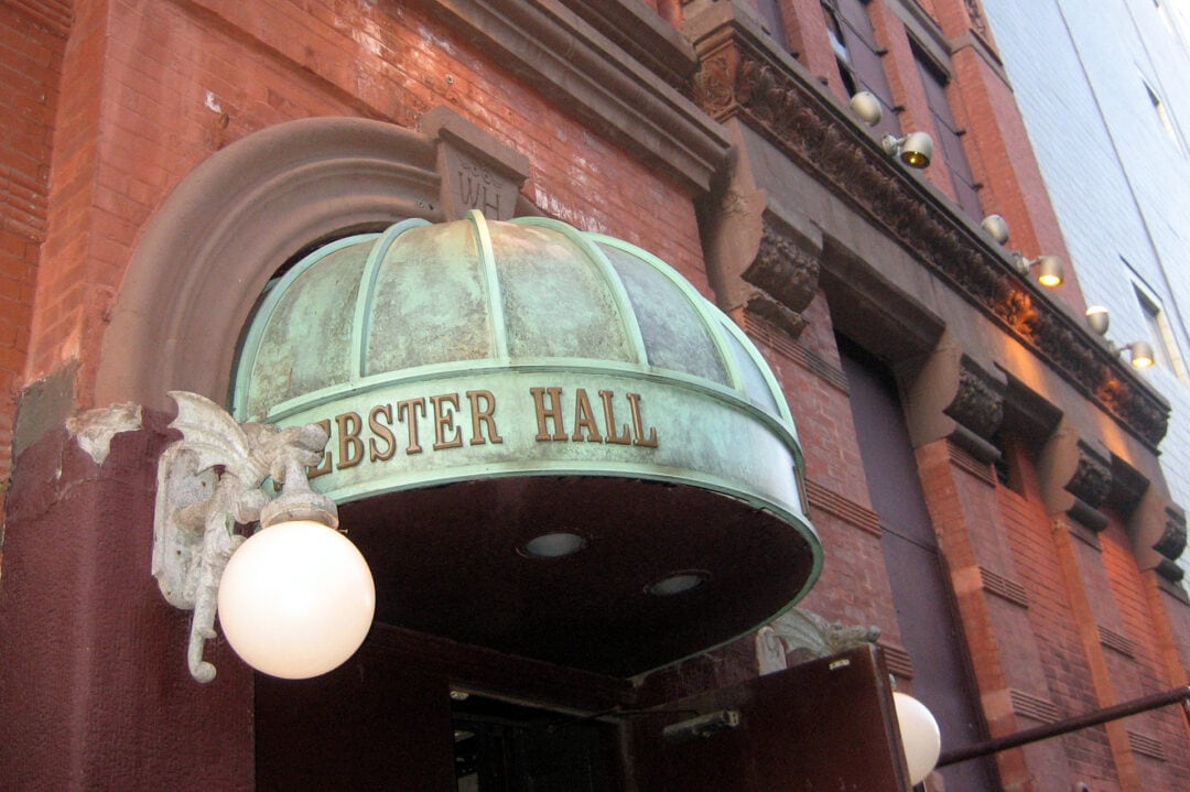 a red brick building with a green oxidized copper awning that says webster hall