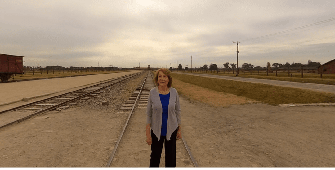 Fritzie Fritzshall standing on the train tracks near Auschwitz