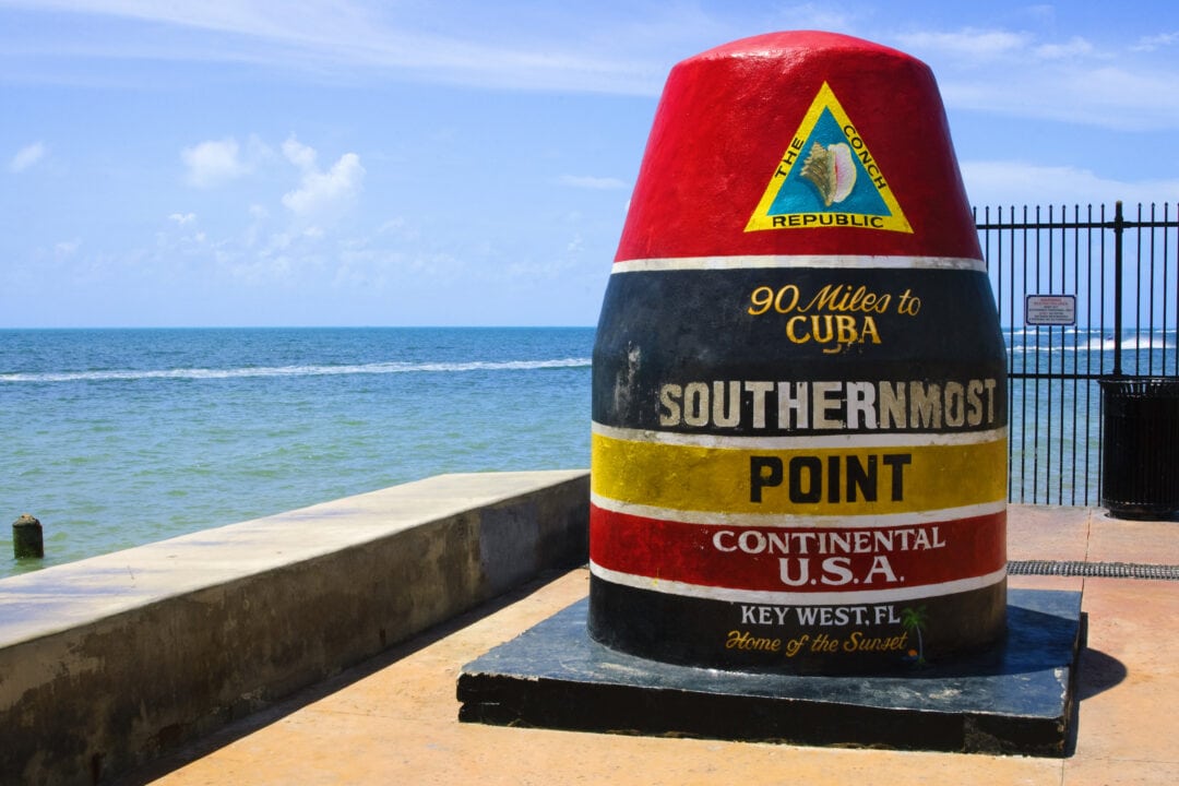 a black, red, white, and yellow concrete buoy says 90 miles to cuba, southernmost point in the continental U.S.A. in key west, Florida