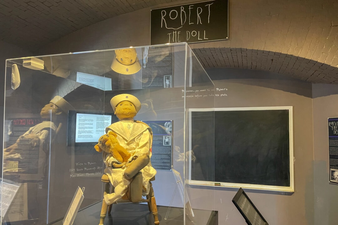 a doll in a glass case with a sign that says "robert the doll" above it