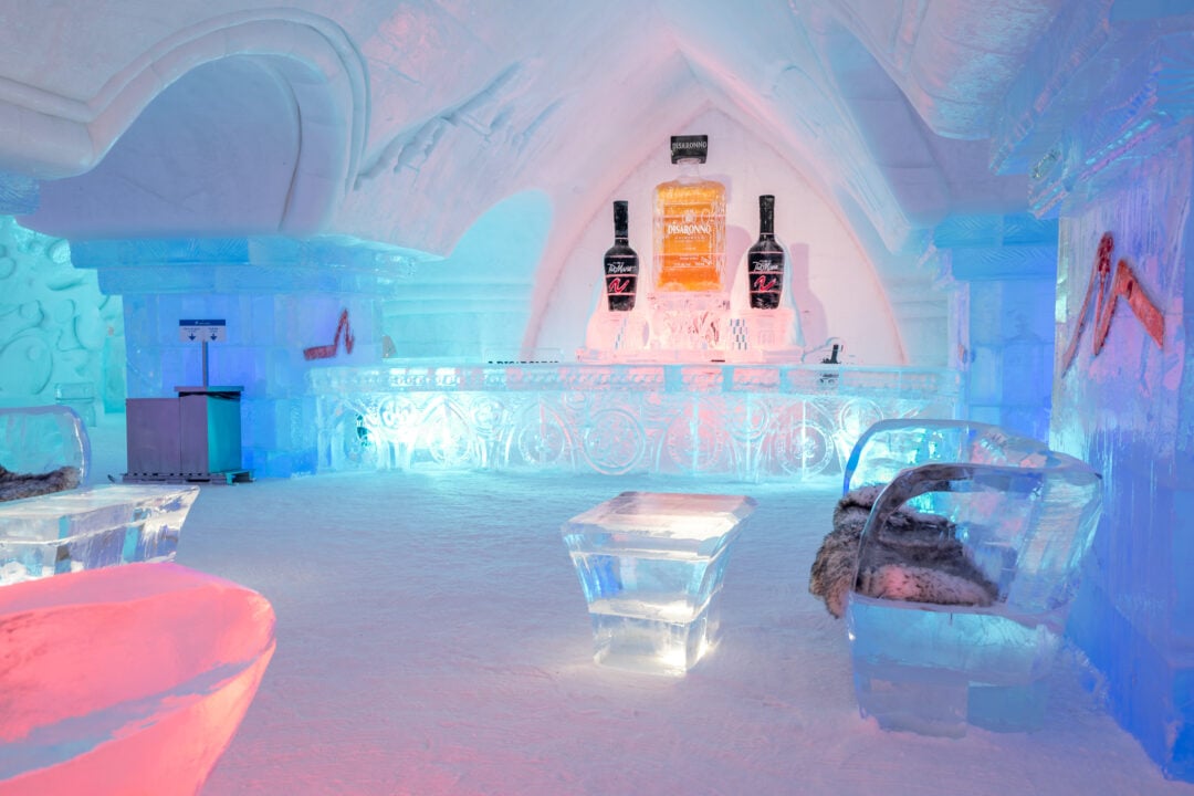 the interior of an ice hotel with colored lights and an ice bar