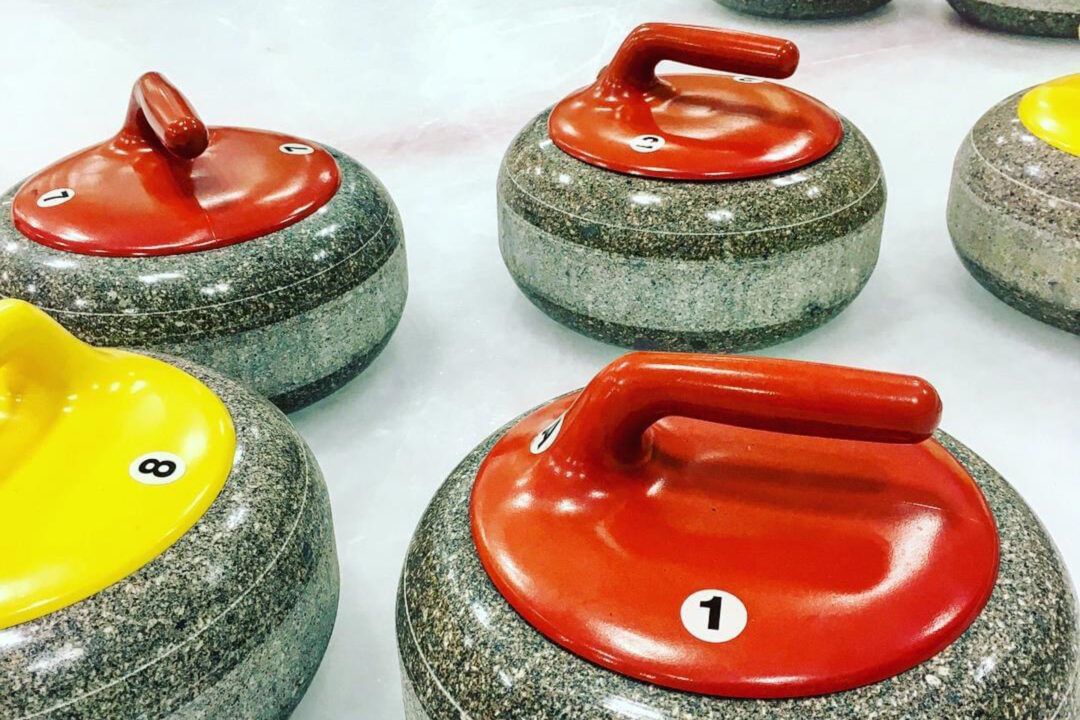 red and yellow curling discs sitting on ice