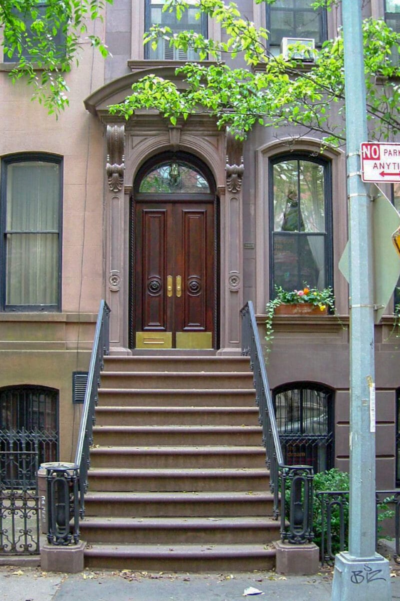 the ornate door of a brownstone and stoop on a city street