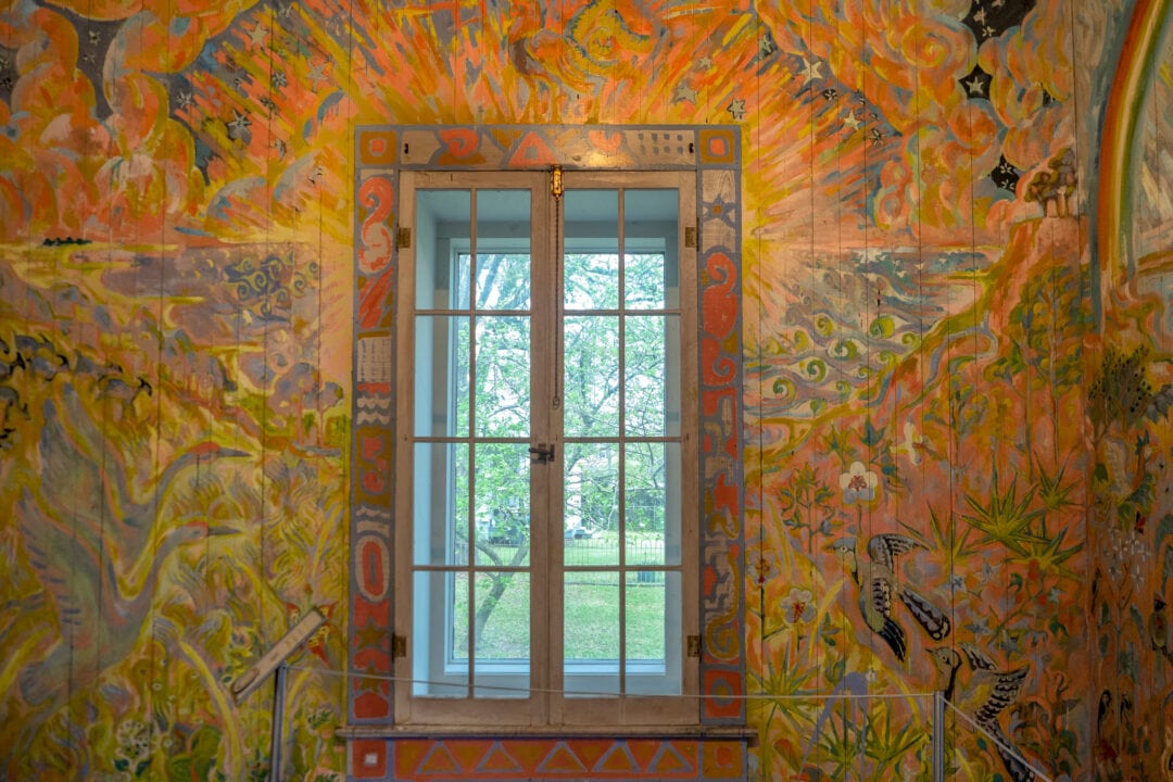 a brightly colored painting on a wall with a window in the center