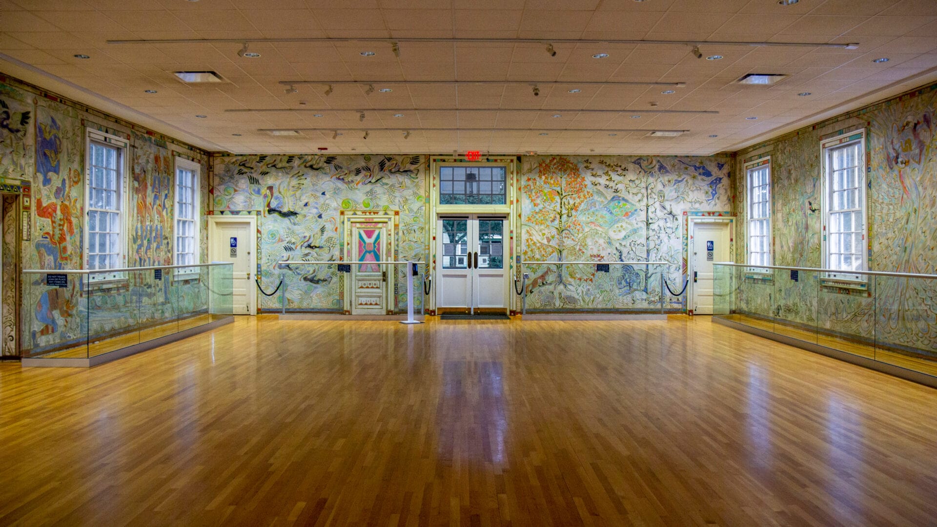 a large, empty room with shiny hardwood floors and colorfully painted walls