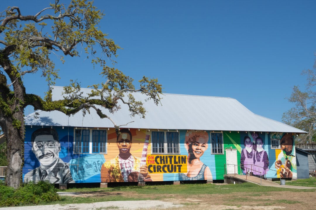 A colorful Chitlin' Circuit mural on the side of a one-story clapboard building