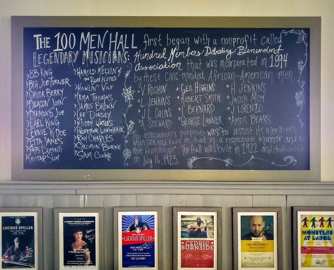 A blackboard lists famous musical acts that played at the 100 Men Hall