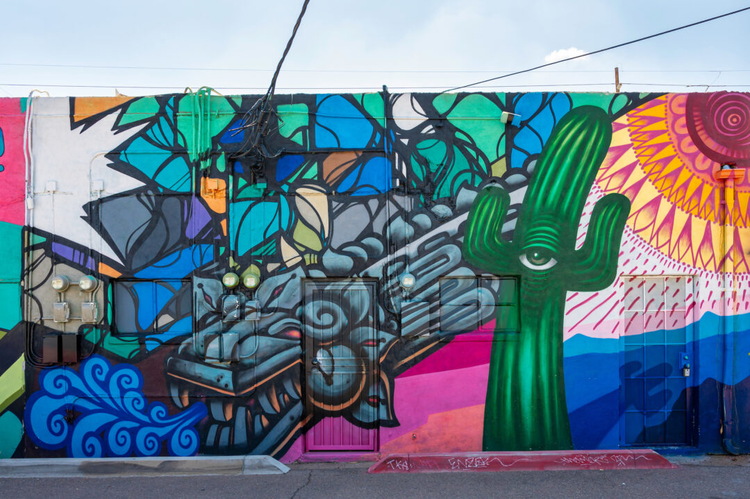 A colorful mural featuring a one-eyed cactus and other abstract objects