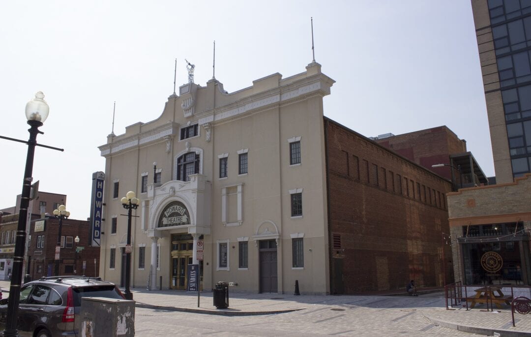 a four-story neoclassical theater facade with brick building and sign that says howard theater