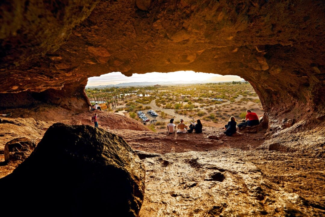 People sitting inside the Hole-in-the-Rock rock formation at Papago Park.