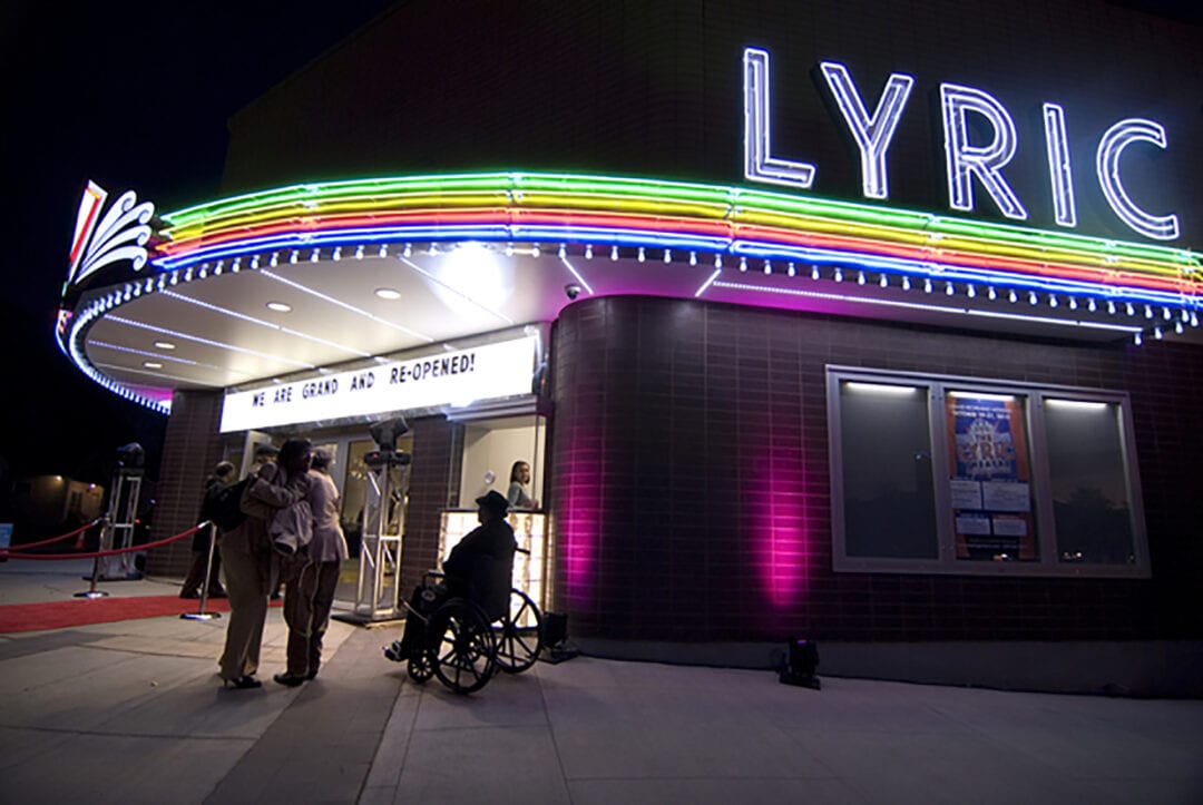 a striped neon sign at night at the facade for the lyric theater